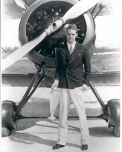 Hughes in front of bi-plane holding the trophy, after winning All-American Air Meet in Miami in the category "sportsman pilot free-for-all," 1934.